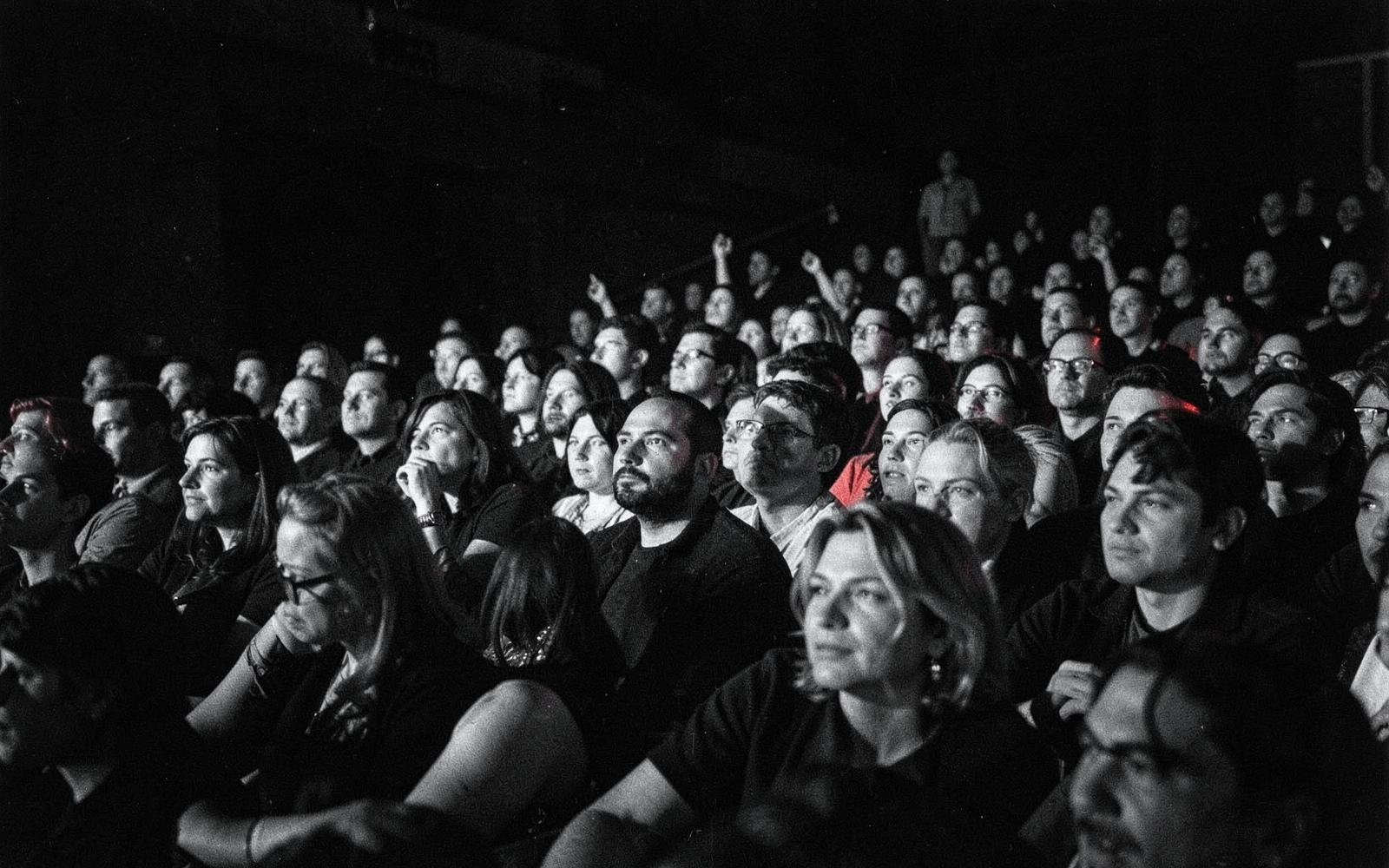 Audience in a dark theatre watching a talk
